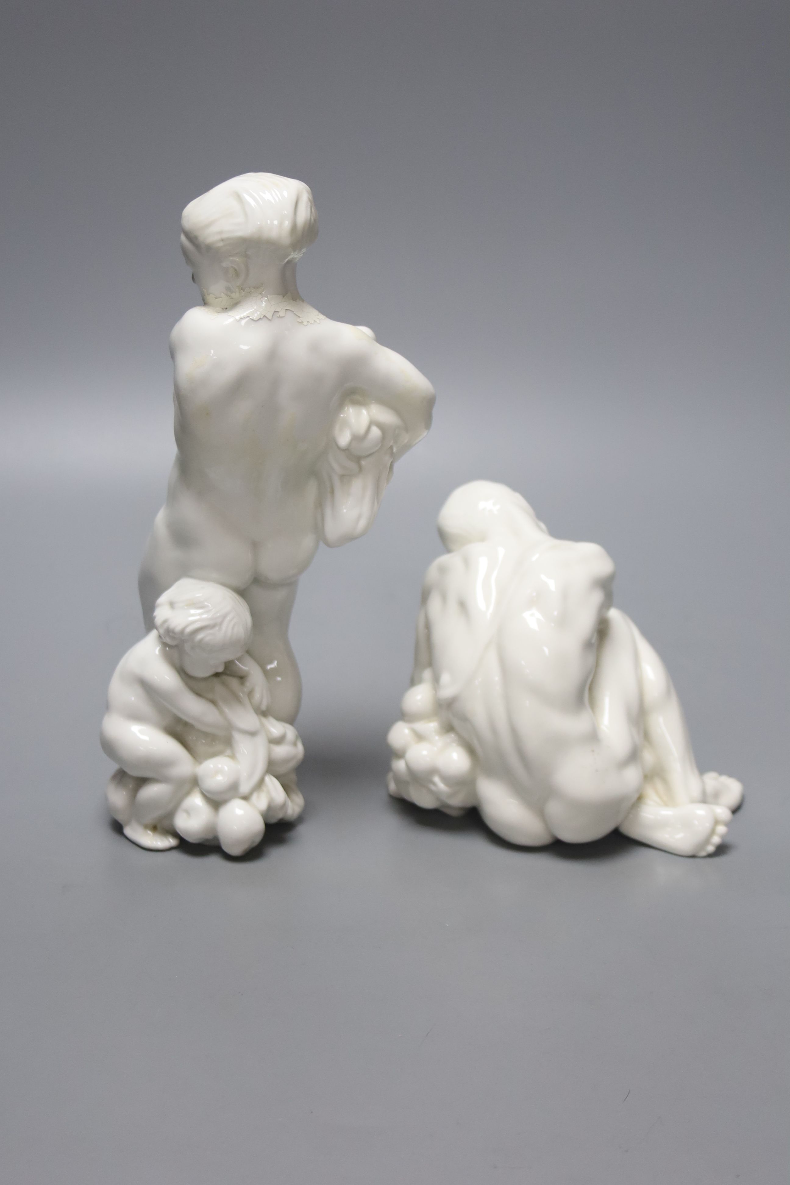 Kai Neilsen (1882-1924) for Bing & Grondahl, Woman with harvest and child, model 4031, 22 cm and seated man holding grapes, model 4024, height 24cm